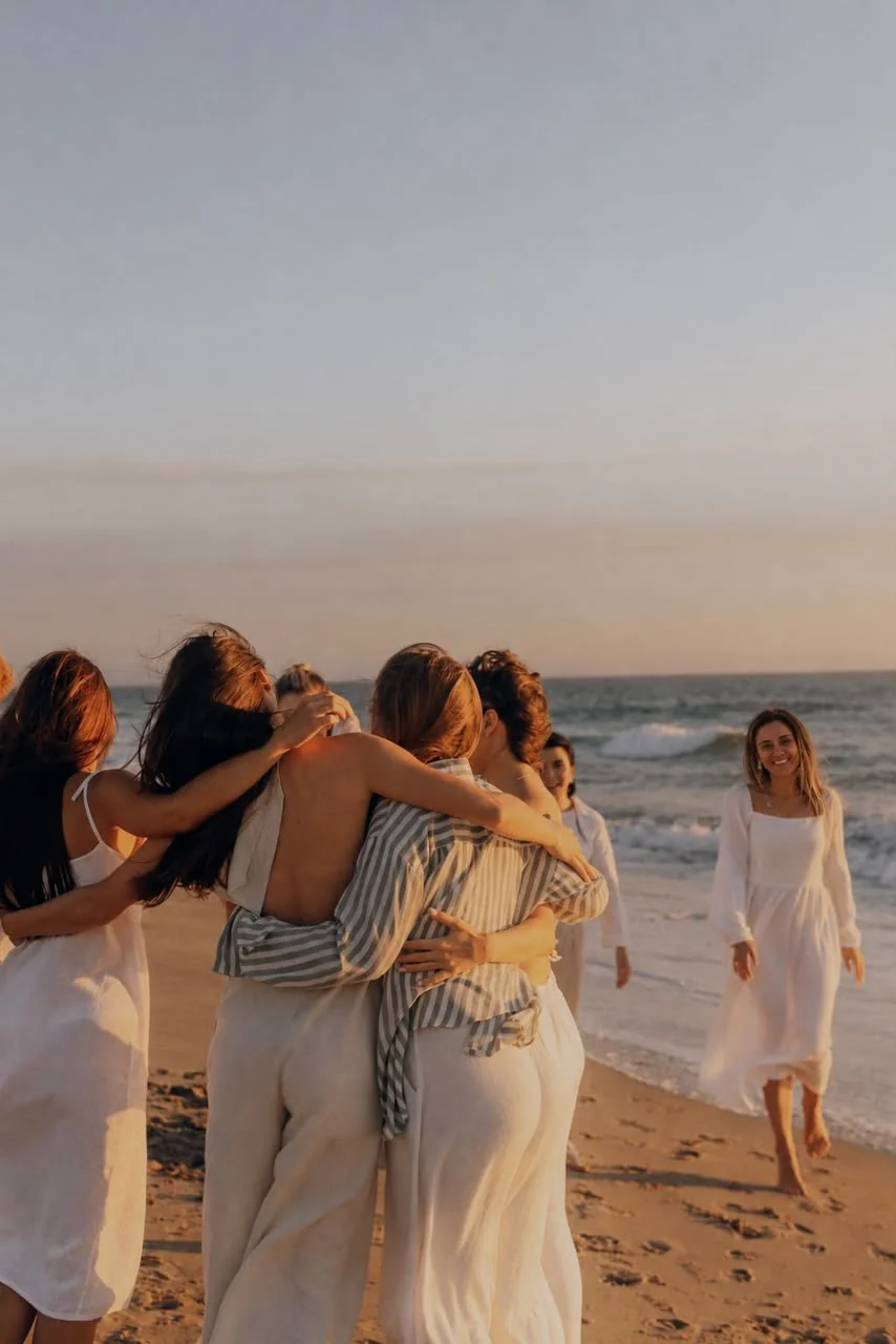 Personas abrazándose en una playa al atardecer.
